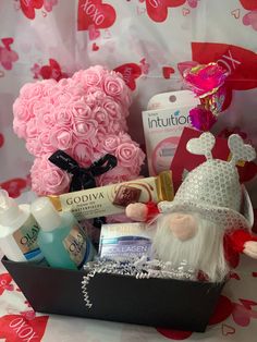 a pink teddy bear sitting on top of a table next to a basket filled with items