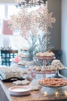 a table topped with lots of desserts next to a snowflake and christmas tree