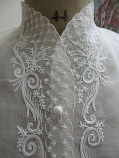 the back of a mannequin's dress with white lace and flowers on it