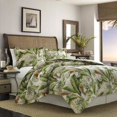 a bed with a green and white comforter next to a window overlooking the ocean