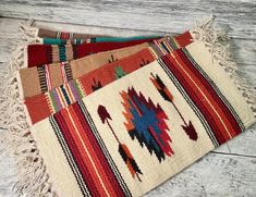 multicolored rug with fringes laying on wooden floor next to wood planks