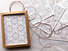 four square frames with red thread in them on top of a white cloth covered table