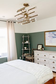 a bedroom with green walls, white bedding and a wooden dresser in the corner