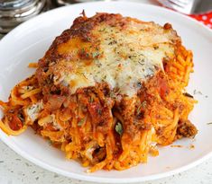 a close up of a plate of food with spaghetti and cheese on it, sitting on a table