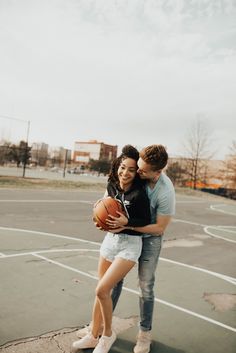 a man and woman hugging each other in an outdoor basketball court