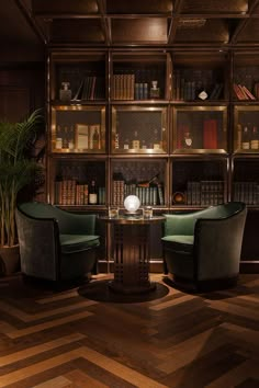 two green chairs sitting in front of a wooden book shelf filled with lots of books