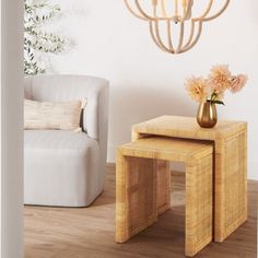 two tables with flowers on them in front of a white chair and chandelier