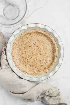 an uncooked pie crust in a glass pie dish on a marble countertop