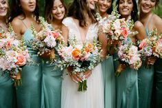 a group of bridesmaids in green dresses holding bouquets and smiling at the camera