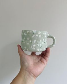 a hand holding up a small cup with daisies on the outside and white flowers on the inside