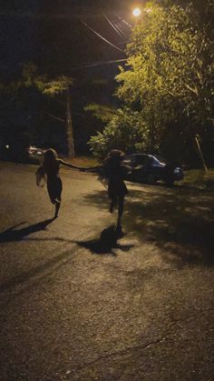 two people are running down the street at night