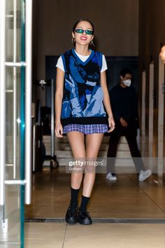 a woman walking down a hallway wearing sunglasses