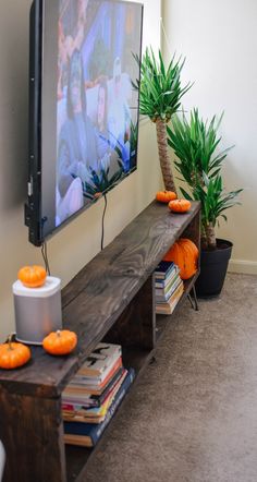 a flat screen tv sitting on top of a wooden shelf next to potted plants