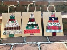 three bags with christmas trees on them are sitting next to each other in front of a brick wall