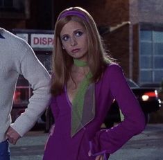 a man and woman standing next to each other on a city street in front of a building