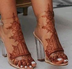 a woman's feet with henna tattoos on their ankles and legs, both wearing high heeled sandals