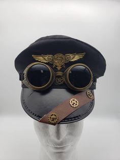 Black police-style steampunk hat with leather and gold gear trim, aviator wings, and goggles attached. One size. SHOP POLICIES: Orders placed Monday-Friday generally ship next day. Orders placed Saturday/Sunday ship the following Tuesday. Cancellations are permitted before an item ships. Please note that we do not accept returns. Steampunk Police, Aviator Aesthetic, Steampunk Googles, Steampunk Futuristic, Hat With Goggles, Black Steampunk, Steampunk Items, Police Hat, Steampunk Ideas