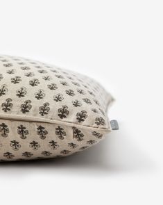 a pillow with black and white designs on the front, sitting on a white surface