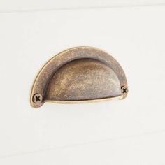 an antique brass door handle on a white painted cabinet with two screw holes in the middle