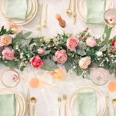 the table is set with pink and green flowers, gold cutlery, and silverware