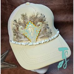 Tan foam trucker hat with feathers and bull and  Aztec hat patch with white beaded hat chain Western White Trucker Hat With Curved Brim, Western Style White Trucker Hat With Curved Brim, White Adjustable Trucker Hat For Rodeo, White Western Snapback Baseball Cap, Western Style White Snapback Hat With Curved Brim, White Western Style Snapback Baseball Cap, White Snapback Hat For Festivals, Western White Snapback Hat, White Western Snapback Hat