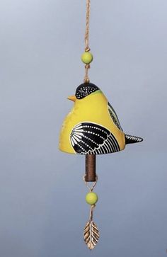 a yellow bird hanging from a wooden pole