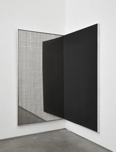 two black and white paintings in an empty room with concrete flooring on the ground