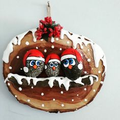 an ornament with three penguins wearing santa's hats on top of a piece of wood