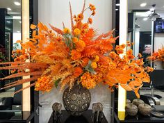 a vase filled with orange flowers sitting on top of a black table next to a mirror