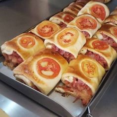 many sandwiches are lined up on a metal tray and ready to be cooked in the oven