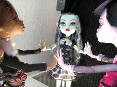 two dolls are talking to each other in front of a mirror and another doll is holding her hand out