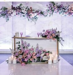 a table with candles and flowers on it in front of a wall hanging from the ceiling