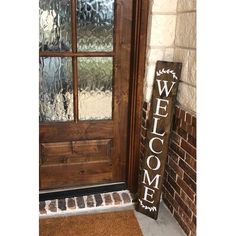 a welcome sign sitting in front of a wooden door with glass panes on it