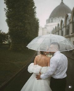 a bride and groom under an umbrella in the rain