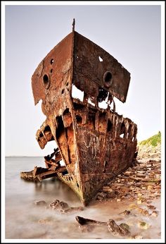 an old rusted boat sitting on top of a beach