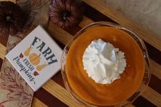 a glass bowl filled with whipped cream next to a box of farm pumpkin puree