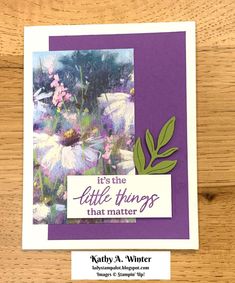 a close up of a card on a wooden surface with flowers and leaves in the background