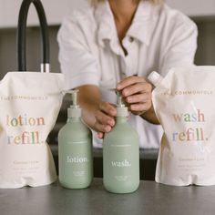 a woman sitting at a table with two bottles of lotion and a bag on the counter