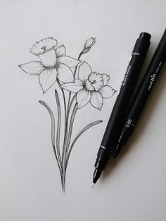 two pens are sitting on top of a piece of paper with flowers drawn on it