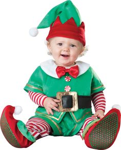 a baby dressed in an elf costume sitting on the ground with his legs spread out