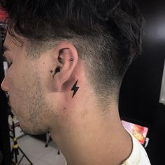 a man's ear has a lightning tattoo on his left side behind the ear