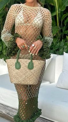 a woman in a fishnet dress holding a straw bag