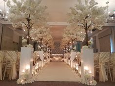 an aisle decorated with white flowers and candles