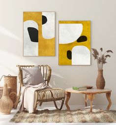 two paintings hang on the wall next to a chair and table in a living room