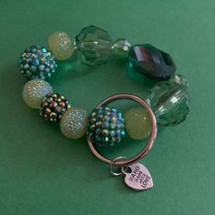 a bracelet with beads and charms on a green surface, next to a keychain