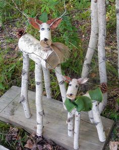 two deer made out of birch trees with green scarfs on their heads and legs