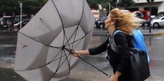 a woman walking across a street holding an umbrella