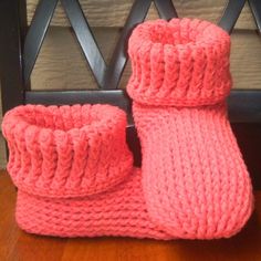 a pair of pink knitted boots sitting on top of a wooden floor