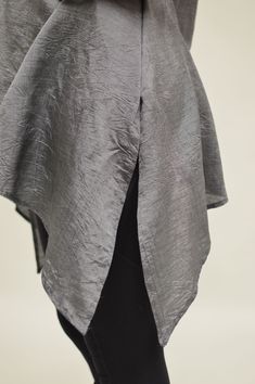 the back of a woman's grey top with black pants and heels on her feet