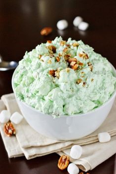 a white bowl filled with green frosting and nuts